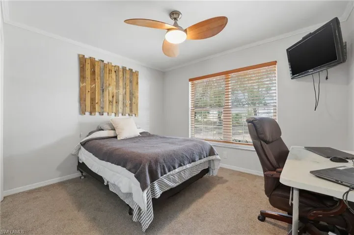 Bedroom with crown molding, light carpet, ceiling fan, and an office area