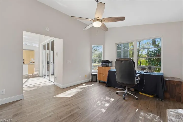 Office with light wood finished floors and a ceiling fan