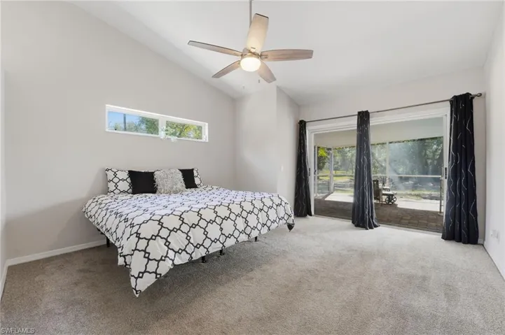 Carpeted bedroom with access to exterior, lofted ceiling, and ceiling fan