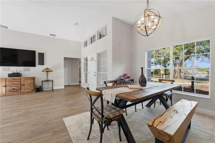 Dining space with a towering ceiling, light wood-style flooring, a chandelier, and french doors