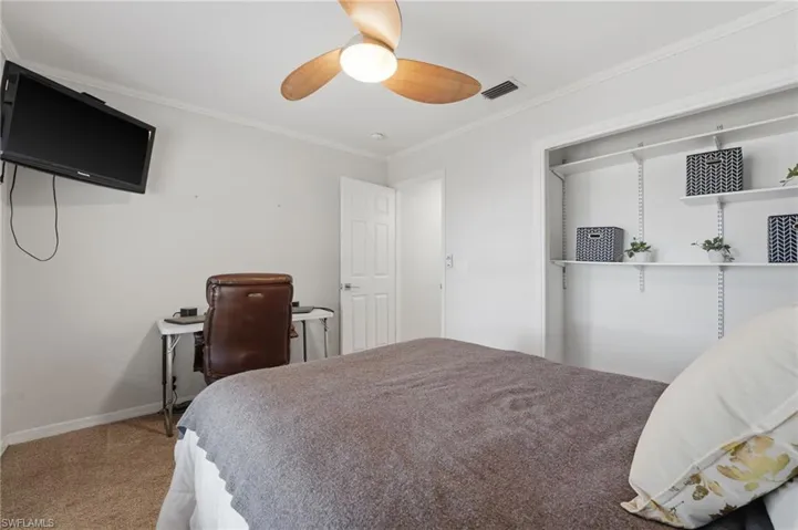 Bedroom with ornamental molding, carpet floors, and ceiling fan