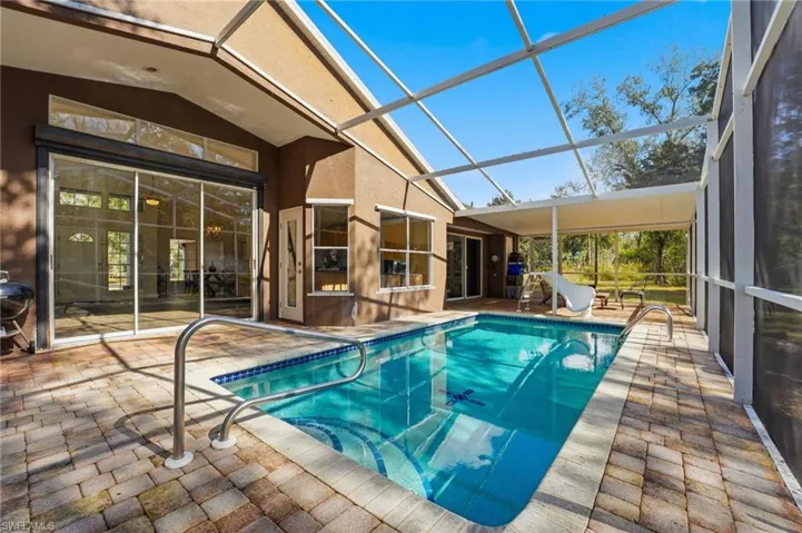 Outdoor pool with a patio, a sunroom, and glass enclosure