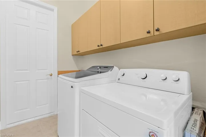 Washroom featuring light tile patterned floors, separate washer and dryer, and cabinet space