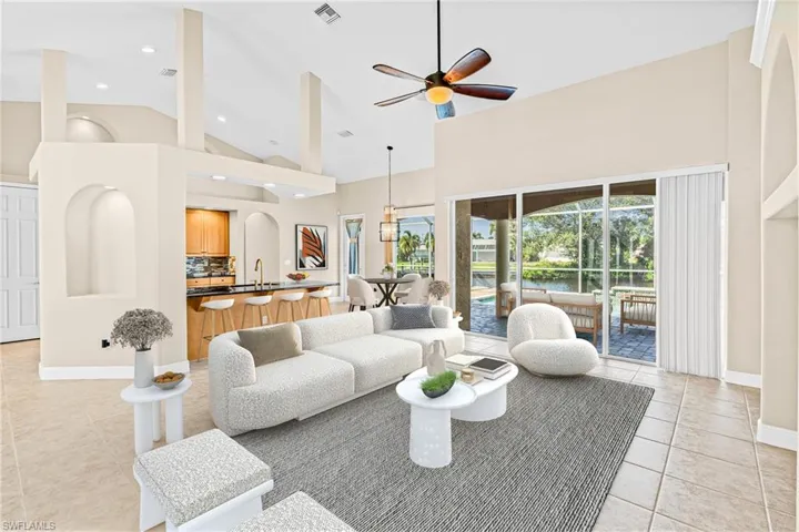 Living area featuring a ceiling fan, high vaulted ceiling, light tile patterned floors, a water view, and a sunroom