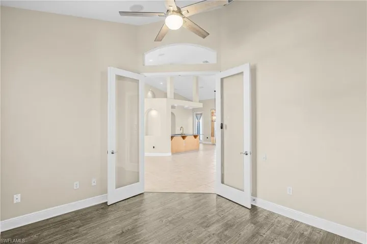 Unfurnished room featuring french doors, wood finished floors, high vaulted ceiling, and ceiling fan