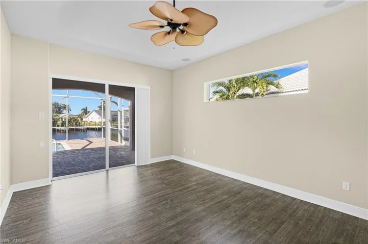Unfurnished room featuring plenty of natural light, dark wood-type flooring, a water view, and ceiling fan