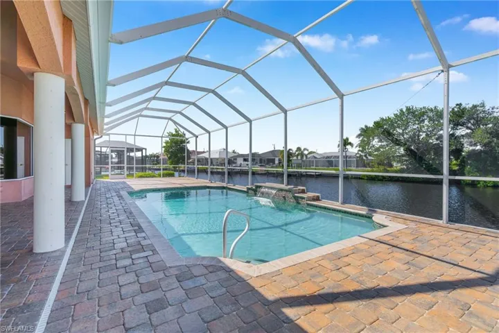 Outdoor pool with a sunroom, a water view, a lanai, and a patio