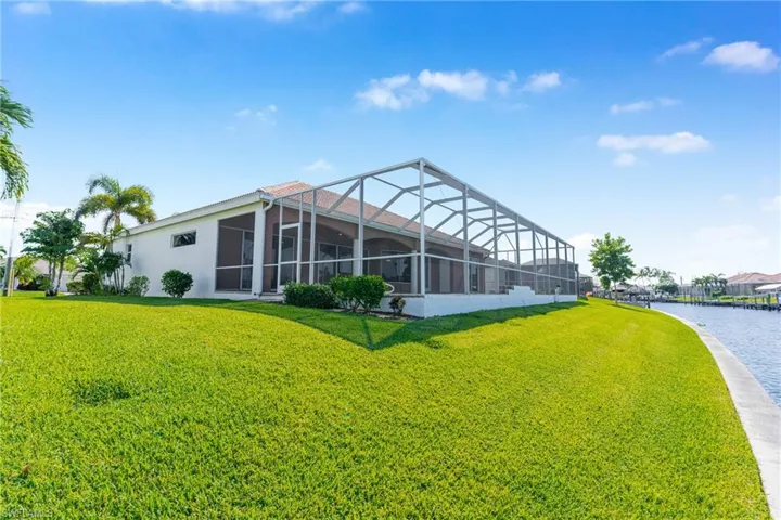 Back of house featuring a sunroom, glass enclosure, and a yard