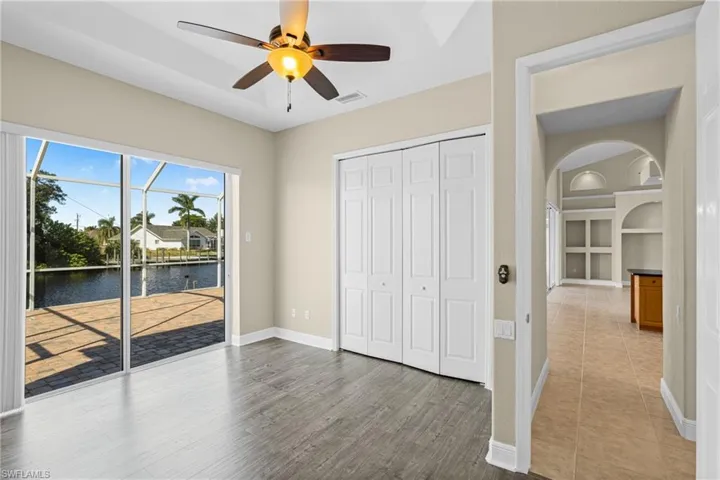 Unfurnished bedroom featuring arched walkways, a water view, access to outside, ceiling fan, and a closet