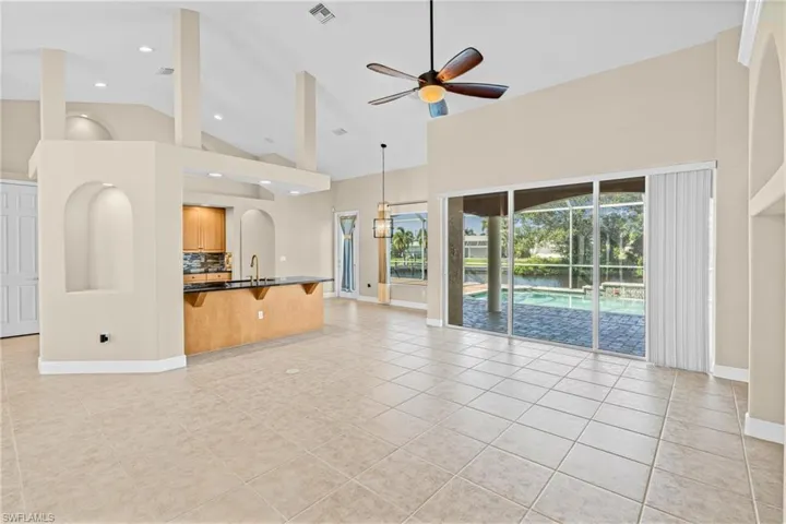 Unfurnished living room with a ceiling fan, high vaulted ceiling, light tile patterned floors, and a sunroom