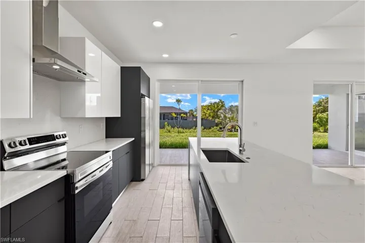 Kitchen featuring plenty of natural light, stainless steel appliances, sink, and wall chimney range hood