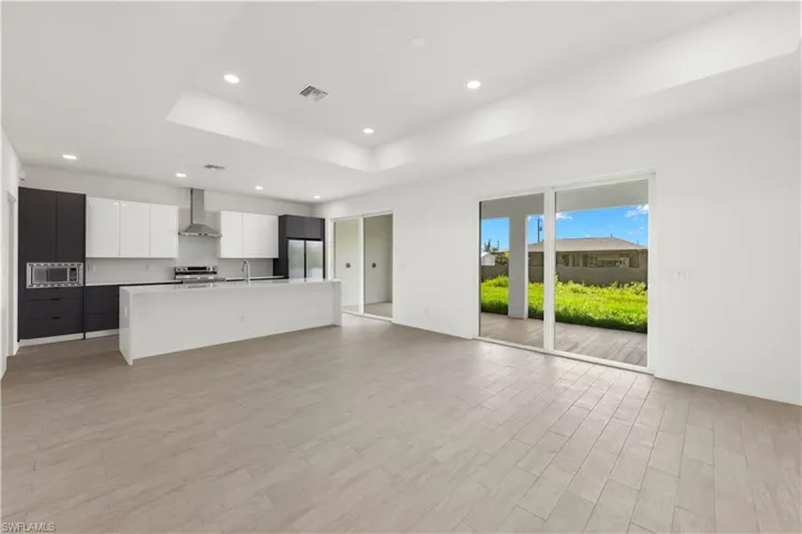 Unfurnished living room featuring a raised ceiling, light hardwood / wood-style flooring, and sink