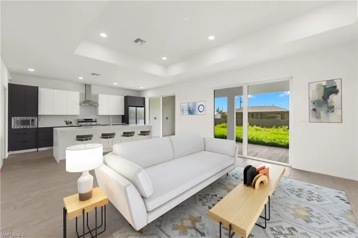 Living room featuring light hardwood / wood-style floors, sink, and a tray ceiling