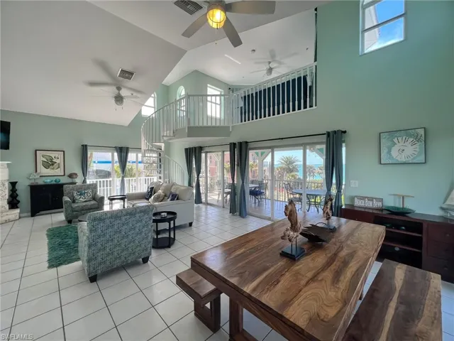 Dining room with light tile patterned floors, high vaulted ceiling, a fireplace, and visible vents