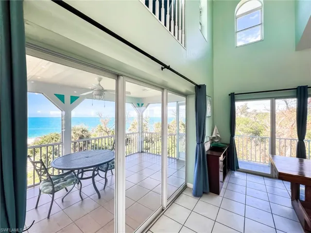 Doorway to outside featuring light tile patterned floors, ceiling fan, a water view, and a towering ceiling