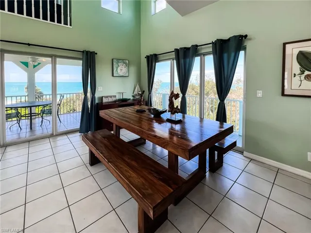 Dining room featuring a water view, light tile patterned floors, a high ceiling, and baseboards