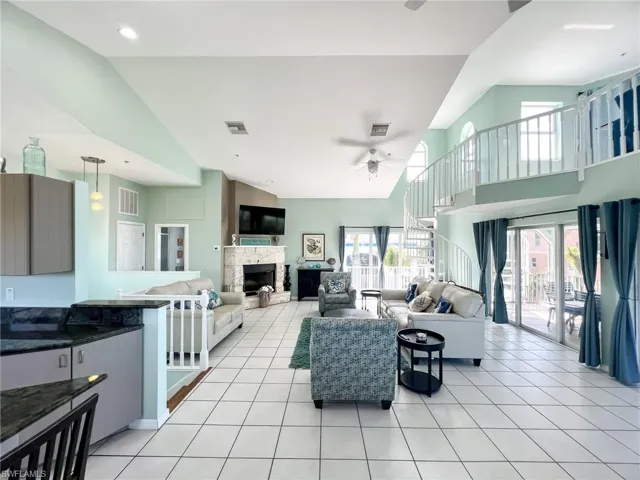 Living room with light tile patterned floors, a fireplace with raised hearth, and plenty of natural light