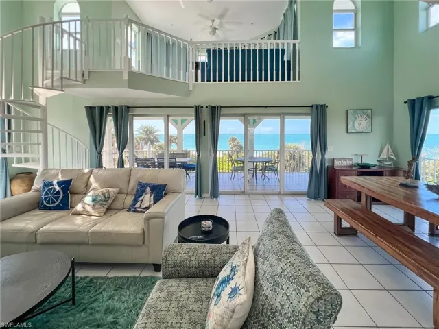 Living area featuring a water view, light tile patterned floors, a towering ceiling, and a ceiling fan