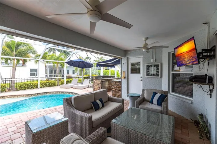 View of swimming pool featuring a patio area, glass enclosure, and ceiling fan