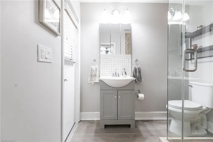 Bathroom with tasteful backsplash, hardwood / wood-style floors, oversized vanity, and toilet