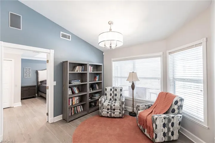 Living area with a healthy amount of sunlight, vaulted ceiling, a chandelier, and light wood-type flooring