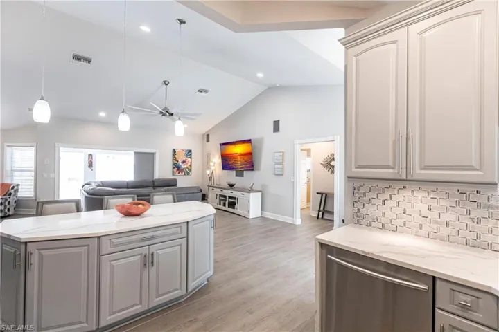 Kitchen featuring light wood-type flooring, gray cabinets, backsplash, pendant lighting, and ceiling fan