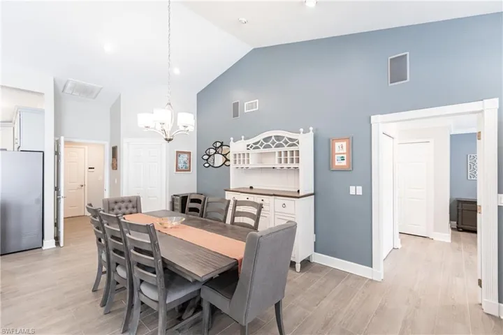 Dining area featuring high vaulted ceiling, light hardwood / wood-style floors, and a notable chandelier