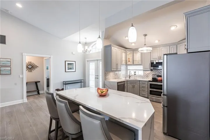 Kitchen with light hardwood / wood-style floors, stainless steel appliances, backsplash, gray cabinetry, and sink