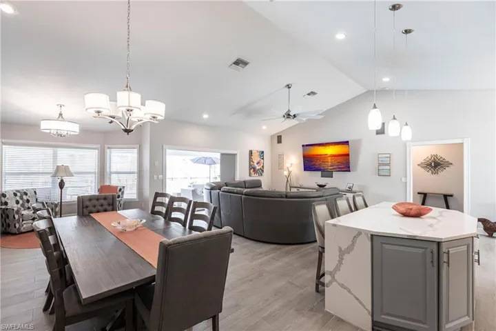 Dining room featuring light hardwood / wood-style floors, vaulted ceiling, and ceiling fan with notable chandelier