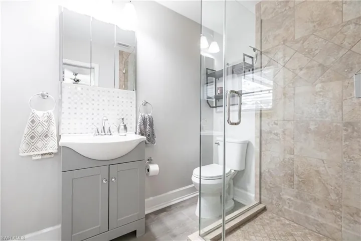 Bathroom with walk in shower, tile flooring, vanity, and toilet