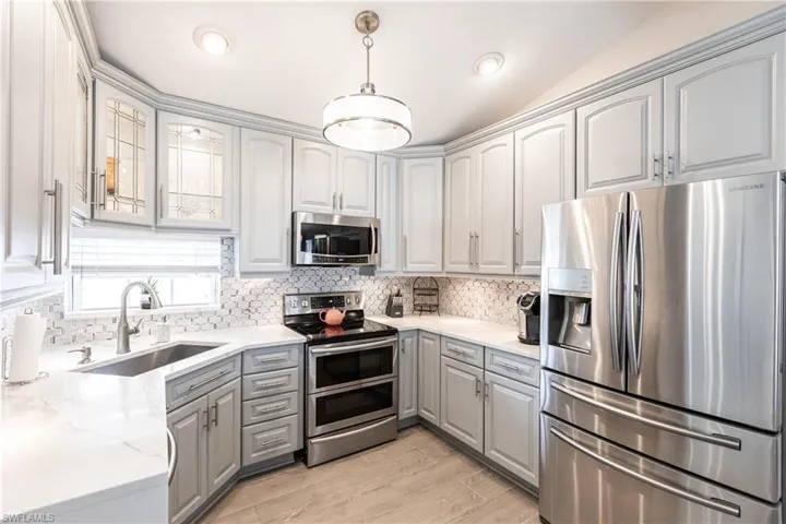 Kitchen with sink, hanging light fixtures, gray cabinetry, and stainless steel appliances
