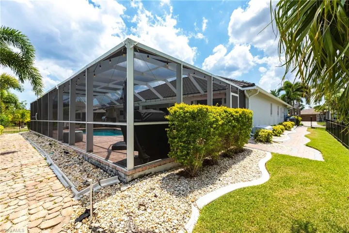 Back of house with a lawn, a lanai, and a fenced in pool