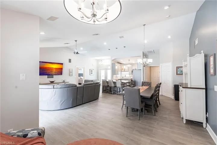 Dining room featuring high vaulted ceiling, light hardwood / wood-style floors, and ceiling fan with notable chandelier