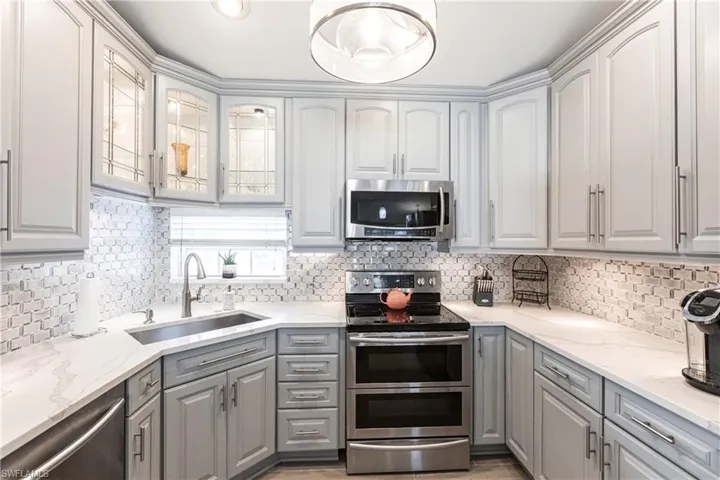 Kitchen featuring stainless steel appliances, gray cabinets, tasteful backsplash, and sink