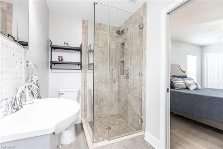 Bathroom with sink, a shower with shower door, and toilet
