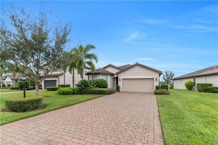 View of front of property featuring decorative driveway, a front lawn, stucco siding, and a garage
