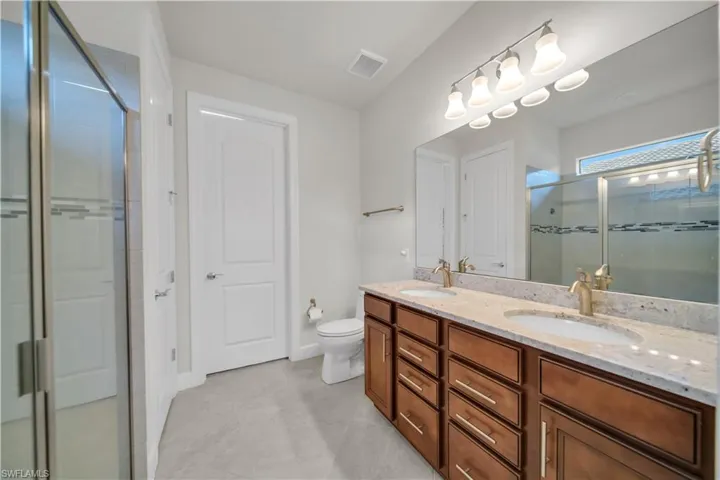 Full bathroom with double vanity and a stall shower