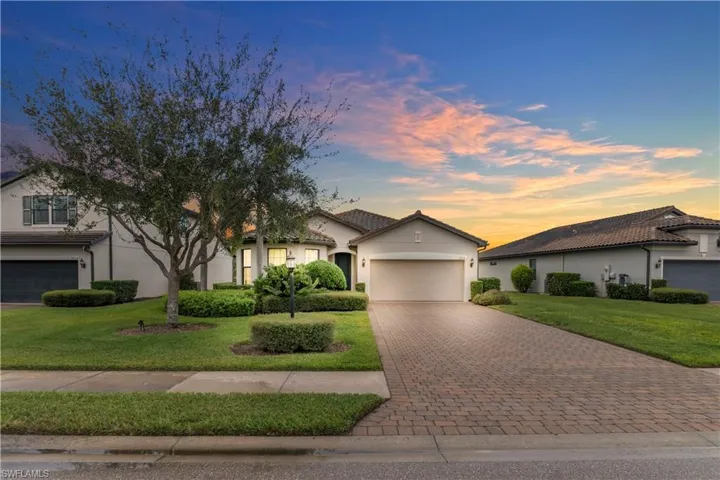 View of front facade with stucco siding, decorative driveway, a garage, and a tiled roof