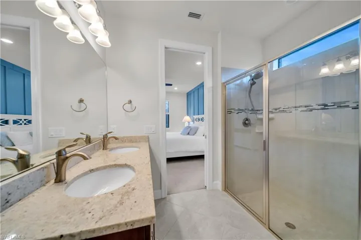 Bathroom with ensuite bath, double vanity, a stall shower, recessed lighting, and a chandelier