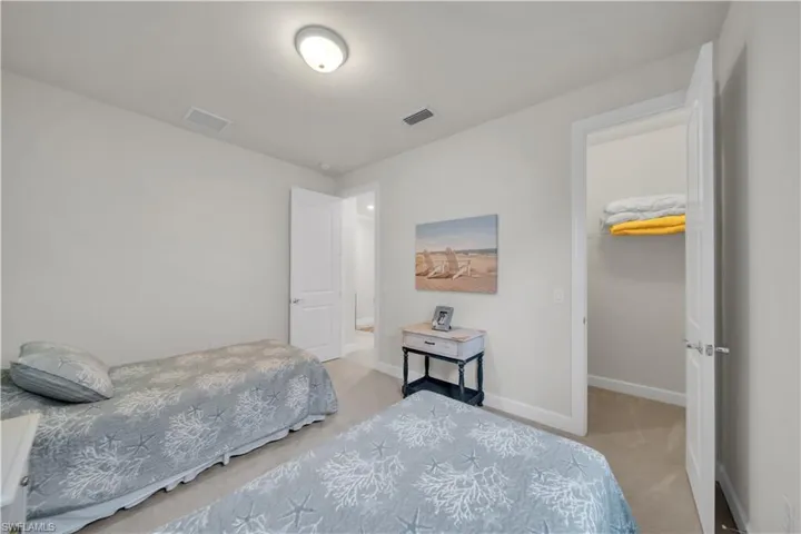 Bedroom with light carpet and a walk in closet