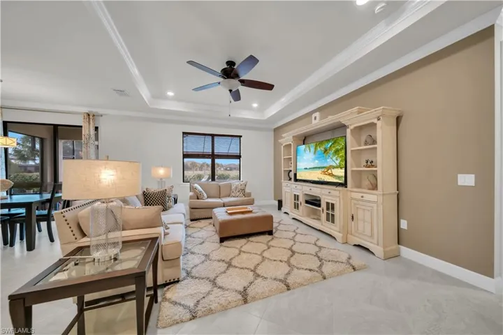 Living room featuring crown molding, recessed lighting, a tray ceiling, ceiling fan, and light tile patterned floors