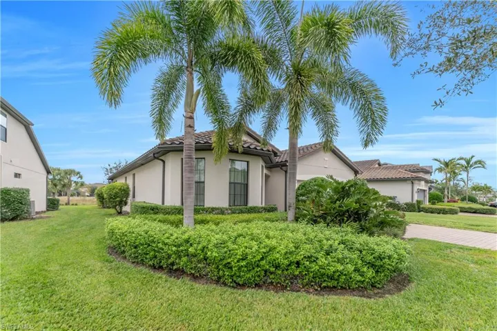 View of side of home featuring a lawn, stucco siding, and a tile roof