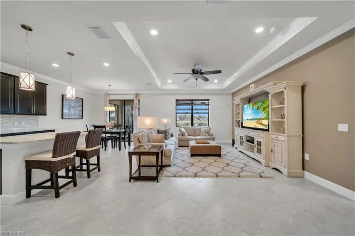 Living area with ornamental molding, recessed lighting, ceiling fan, and a tray ceiling