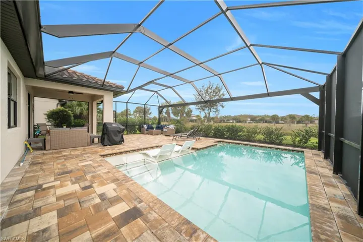 Outdoor pool featuring a sunroom, a patio, glass enclosure, an outdoor hangout area, and grilling area