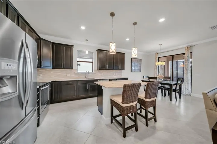 Kitchen with stainless steel appliances, backsplash, ornamental molding, a kitchen island, and pendant lighting