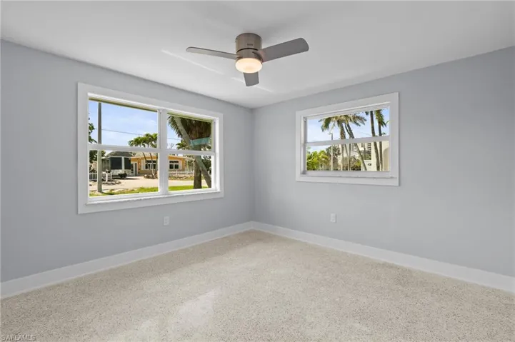 Bedroom featuring terrazzo floor, ceiling fan and baseboards / virtually edited photo.