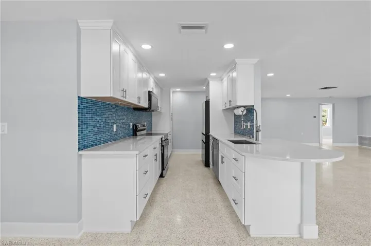 Kitchen with light countertops, visible vents, light, terrazzo floor, appliances with stainless steel finishes, and a sink / virtually edited photo.
