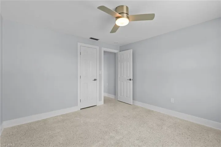 Bedroom with terrazzo floor, ceiling fan, baseboards, and visible vents. Virtually edited image.