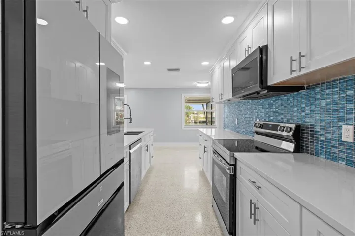 Kitchen featuring visible vents, a sink, appliances with stainless steel finishes, white cabinetry, and backsplash / virtually edited photo.