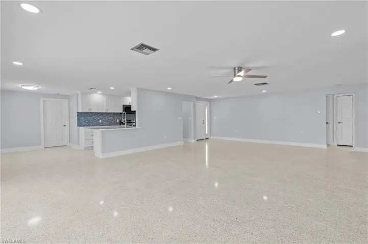 Unfurnished living room with visible vents, baseboards, terrazzo floor, ceiling fan, and recessed lighting / virtually edited photo.